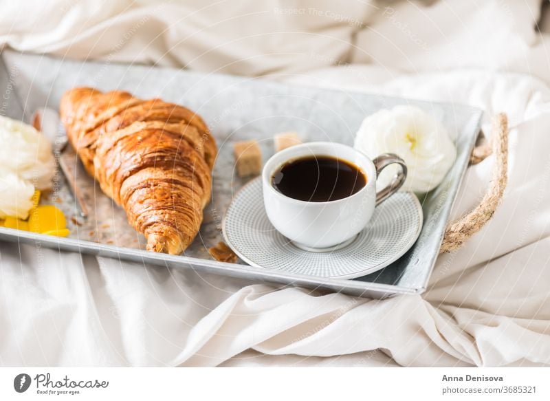 Frisches Croissant, Tasse Kaffee und Hahnenfußblüten. Frühstück im Bett Morgen Romantik Gebäck weiß Tisch Ranunculus Blumen trinken Tablett Espresso süß