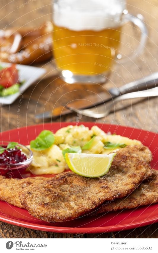 Wiener Schnitzel mit Kartoffelsalat auf dem Teller wiener schnitzel Kalbsschnitzel Petersilie Zitronenscheibe Portion knusprig braun paniert Besteck