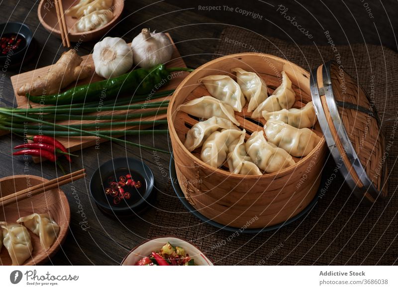 Chinesische gedämpfte Knödel xiaolongbao jiaozi chinesisches Essen Lebensmittel lecker Holz dunkle Speisen Gemüse Salatbeilage Salatgurke Verdunstung