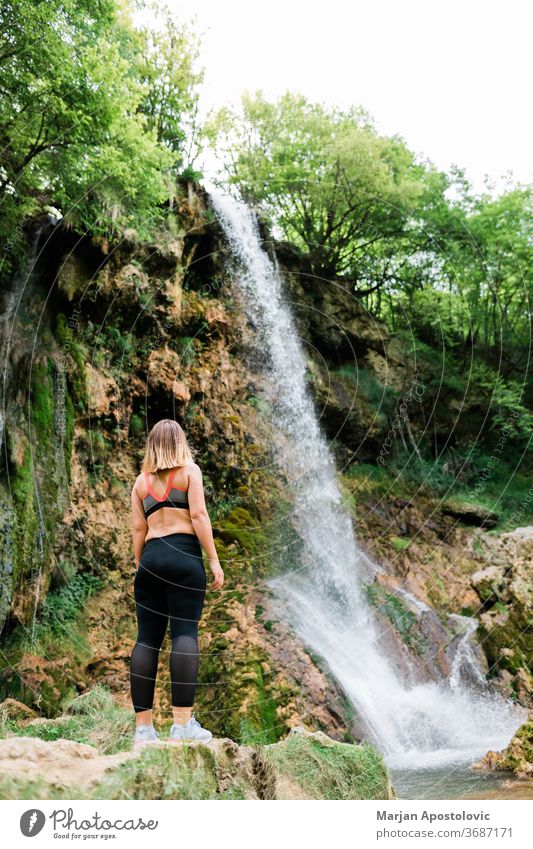 Junge Naturforscherin steht am Wasserfall Errungenschaft aktiv Erwachsener Abenteuer Ehrfurcht Kaskade Kaukasier Ausflugsziel genießend Genuss Umwelt Erkundung