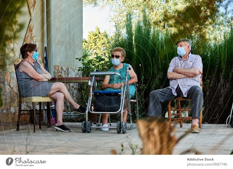 Gruppe von älteren Menschen sitzen auf der Terrasse des Hauses Senior Großeltern sich[Akk] sammeln Hof Zusammensein alt Mundschutz Coronavirus behüten COVID