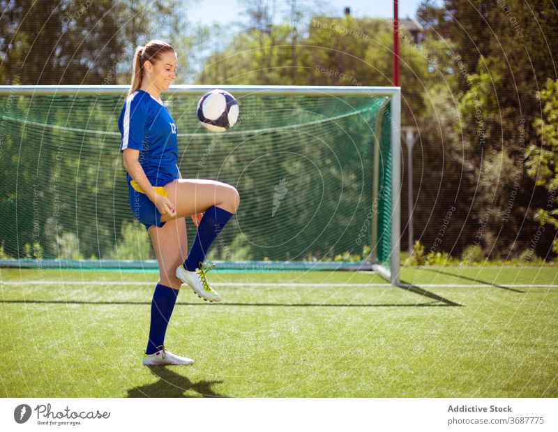 Fröhlicher Fußballspieler jongliert Ball Sportlerin jonglieren Feld Training Lächeln Tor Sommer Uniform Frau sonnig tagsüber Glück Athlet jung Wohlbefinden