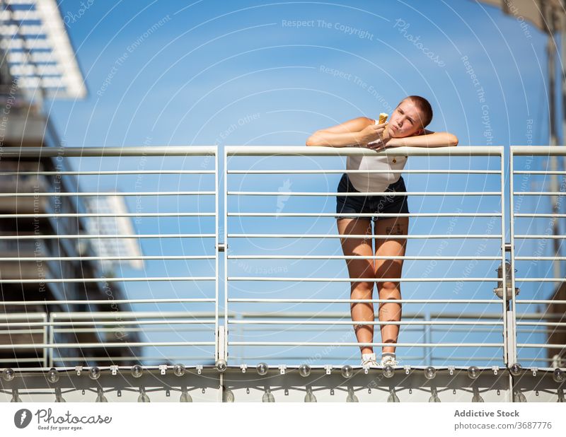 Junge Frau isst Eiscreme auf Brücke essen Speiseeis Großstadt fettarm Reling urban modern Sommer rasiert Kurze Haare Subkultur Individualität jung