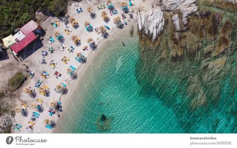 Griechisch-mediterrane Landschaftsdrohne mit Badegästen am Strand von Kavourotripes erschossen. Luftaufnahme der Halbinsel Sithonia Chalkidiki mit felsiger Küste, kristallklarem Wasser und Meeresgrund mit Sonnenschirmen.