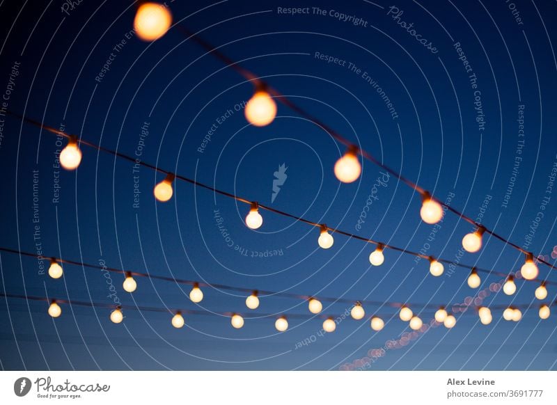 Lichter hängen an einem klaren Sommerabend über dem Kopf Lichterketten Abend Nacht Glühbirnen festlich im Freien patio Hinterhof Party Spaß blau Klarer Himmel