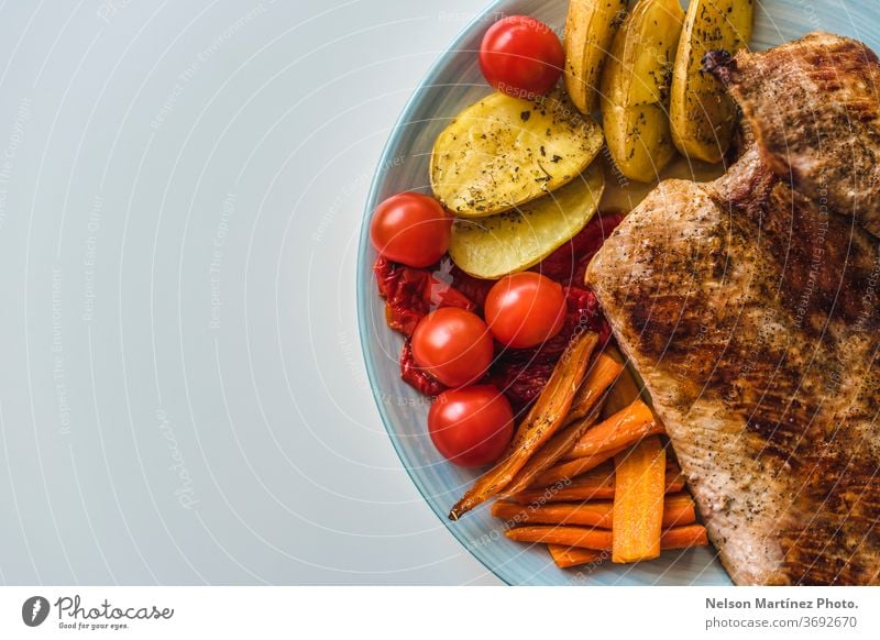 Gegrilltes Fleisch mit Gemüse. Tomaten, Karotten und Kartoffeln. Gesundes Essen. Ein flachgelegter Schuss gebratenes Fleisch, Kartoffeln, Karotten und Tomaten auf einem Teller