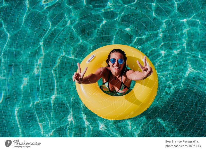 Draufsicht auf eine glückliche junge Frau, die in einem Pool in einem gelben Donut schwimmt. Sommer und lustiger Lebensstil gelbe Donuts aufblasbar Schwimmsport