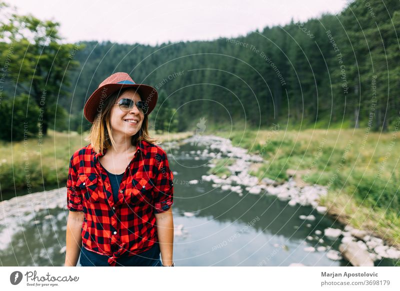 Junge Frau genießt die freie Natur am Fluss in den Bergen aktiv Abenteuer lässig Bach Fundstück Umwelt Expedition erkunden Entdecker Wald Freiheit Mädchen Hut