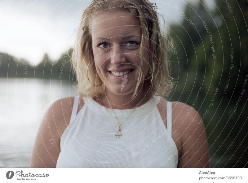 Nahes Portrait einer lächelnden, jungen Frau mit Grübchen in einem See junge Frau blond Lächeln Schmuck schön langhaarig Landschaft gebräunt selbstbewußt Sommer