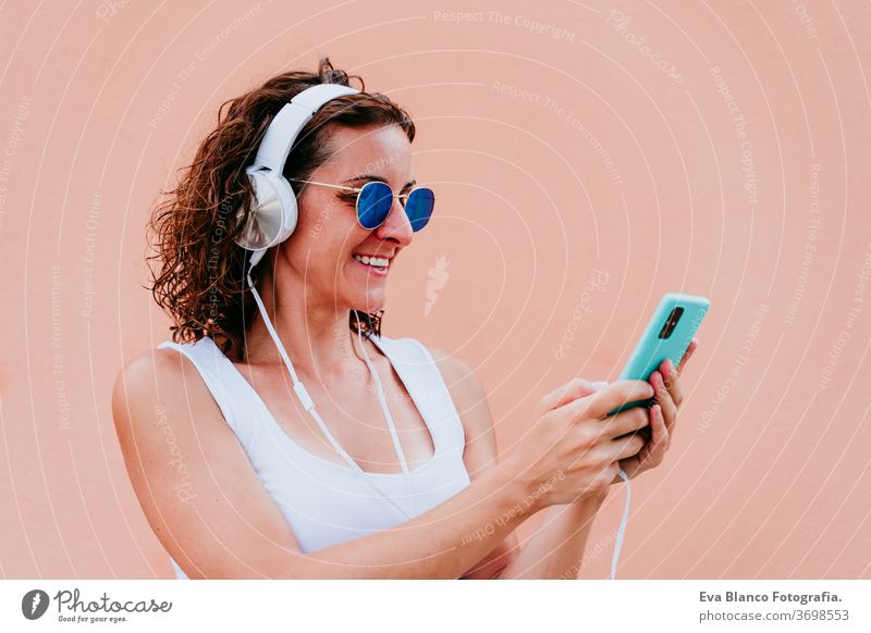 junge glückliche Frau im Freien, die über Kopfhörer und Mobiltelefon Musik hört. Lebensstil in der Stadt. Sommerzeit. Nahaufnahme Handy hören Musik-Headset