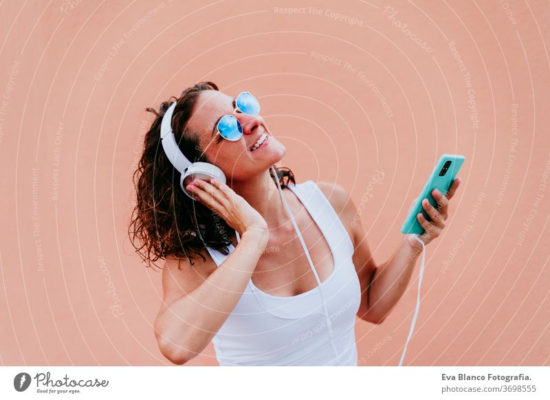 junge glückliche Frau im Freien, die über Kopfhörer und Mobiltelefon Musik hört. Lebensstil in der Stadt. Sommerzeit. Nahaufnahme Handy hören Musik-Headset