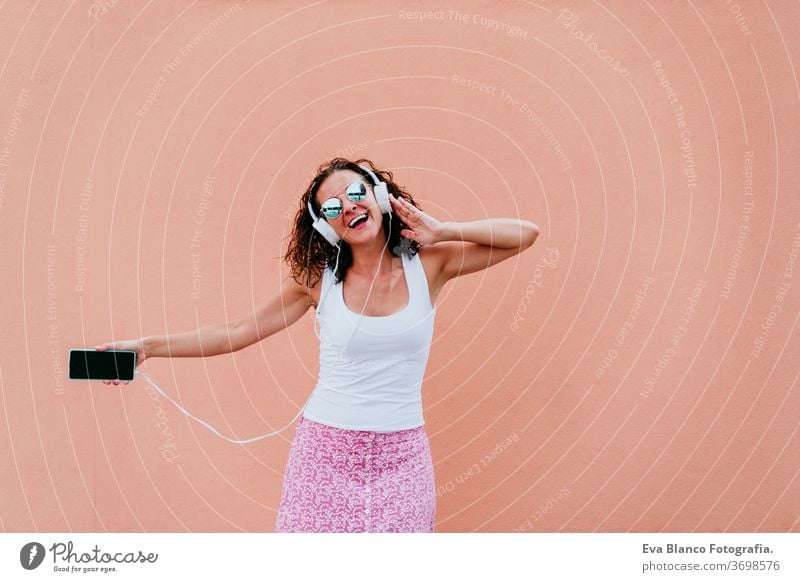 junge glückliche Frau im Freien, die über Kopfhörer und Mobiltelefon Musik hört. Lebensstil in der Stadt. Sommerzeit Handy hören Musik-Headset Großstadt urban