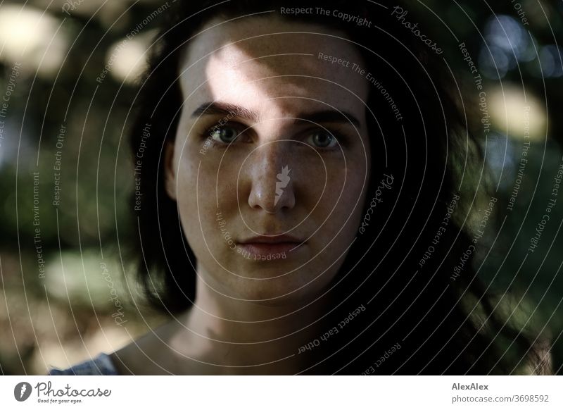 Nahes Portrait einer sommersprossigen Frau in einem Wald im Sommer zart Schatten Licht sportlich feminin Empathie Gefühle emotional Blick in die Kamera Porträt