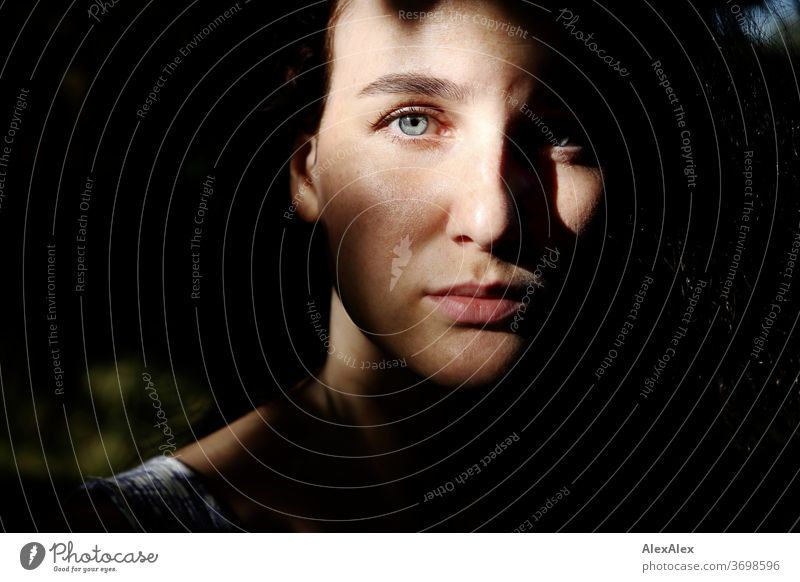 Nahes Portrait einer sommersprossigen Frau in einem Wald im Sommer zart Schatten Licht sportlich feminin Empathie Gefühle emotional Blick in die Kamera Porträt