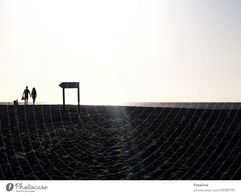 Am Strand von der Düne Helgoland spaziert ein Pärchen an einem Wegweiser vorbei. Sind sie ihm gefolgt? Nordsee Außenaufnahme Farbfoto Natur Tag Umwelt