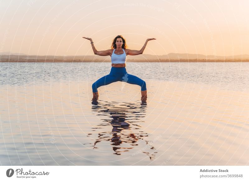 Junge Frau in Göttin Asana reflektiert in See Wasser Yoga üben Pose Ukata Konasana stehen Harmonie Sprit Geist Anmut Fokus Reflexion & Spiegelung Gleichgewicht