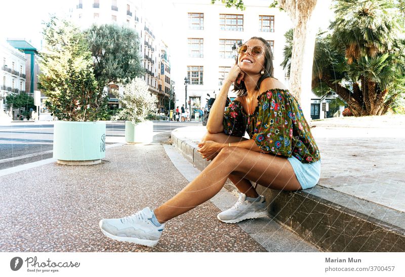 CHICA SONRIENDO SANTADA EN EL BORDILLO FELIZ CALLE SONRISA GAFAS DIA BLOG ESTILO MODA MODERNA BELLA