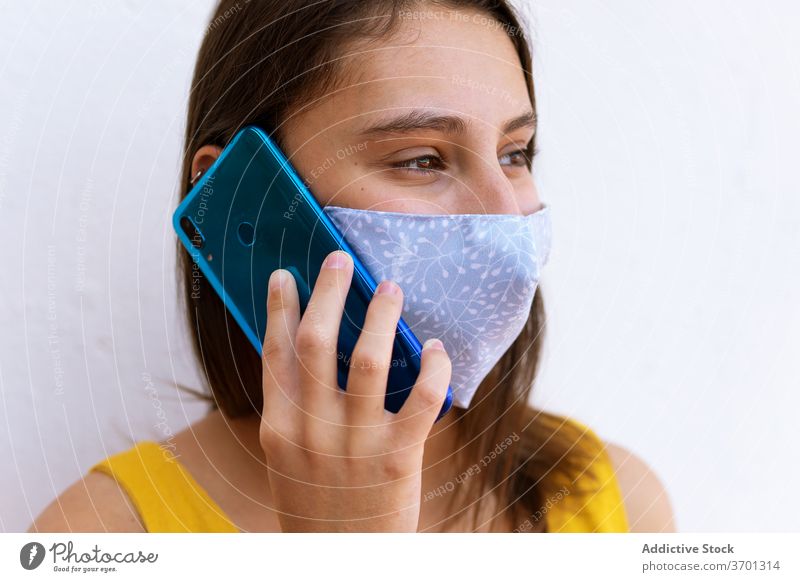 Frau in Maske spricht auf Smartphone reden Mundschutz medizinisch Coronavirus Großstadt diskutieren benutzend Seuche Straße Mobile Gespräch Anruf Telefon