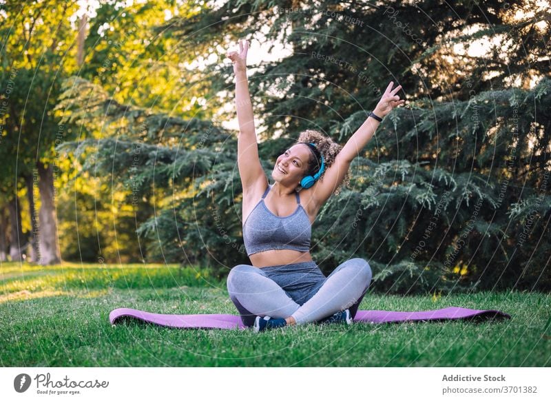 Fröhliche Sportlerin beim Musikhören mit Kopfhörern im Park Frau sportlich zuhören Glück heiter Fitness genießen ausrichten Energie jung Smartphone Training