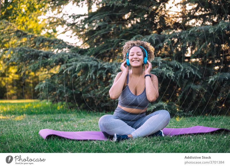 Fröhliche Sportlerin beim Musikhören mit Kopfhörern im Park Frau sportlich zuhören Glück heiter Fitness genießen ausrichten Energie jung Smartphone Training