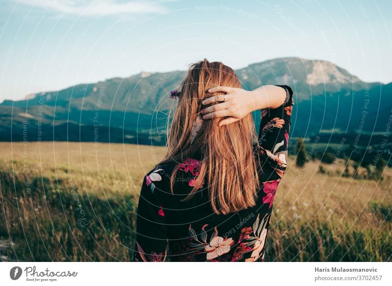 blonde Frau mit Blick auf die Berge der schönen Landschaft Erwachsener Schönheit blauer Himmel Kaukasier Kleid Gesicht Mode Feld Blumenkleid Freiheit Mädchen