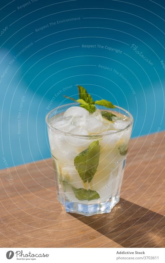 Glas Mojito-Cocktail am Schwimmbad trinken Pool Alkohol Eis Zitrone Minze kalt Getränk Zitrusfrüchte Erfrischung Frucht cool geschmackvoll lecker Feinschmecker