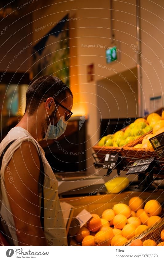 Mann mit Mundschutz/Maske beim Einkaufen im Supermarkt während der Corona Pandemie. Obst Maskenpflicht Geschäft Einzelhandel Alltag Lebensmittel