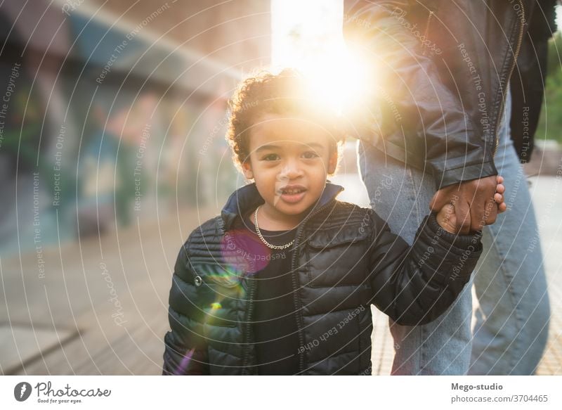 Afroamerikanischer Junge, der die Hand der Mutter hält. schwarz Kind Glück im Freien Menschen Kaukasier Person Afroamerikaner gemischte Rasse Sohn Spaß Genuss