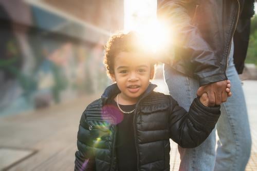 Afroamerikanischer Junge, der die Hand der Mutter hält. schwarz Kind Glück im Freien Menschen Kaukasier Person Afroamerikaner gemischte Rasse Sohn Spaß Genuss