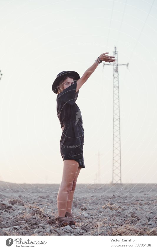 Junge Frau in einem grünen Kleid und einem Hut in einem einsamen Feld auf dem Land Landschaft Freiheitsfrau Wasser Erwachsener lebend Yoga Air Arme abschließen