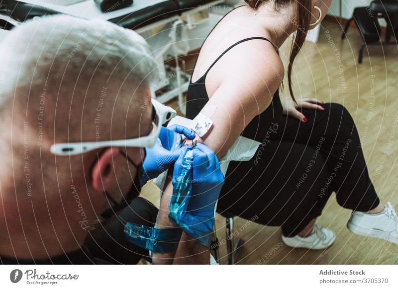 Männlicher Tätowierer macht Tattoo im Salon Meister Mann Maschine bewerben Arbeit Design Nadel männlich Atelier steril Handschuh behüten Mundschutz Tusche Kunst