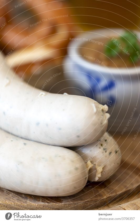 drei bayerische Weißwürste mit Senf Weißwurst Wurst salzig rustikal traditionell Brezel Holztisch Essen Bayern süß Petersilie Mahlzeit Senftopf Oktoberfest