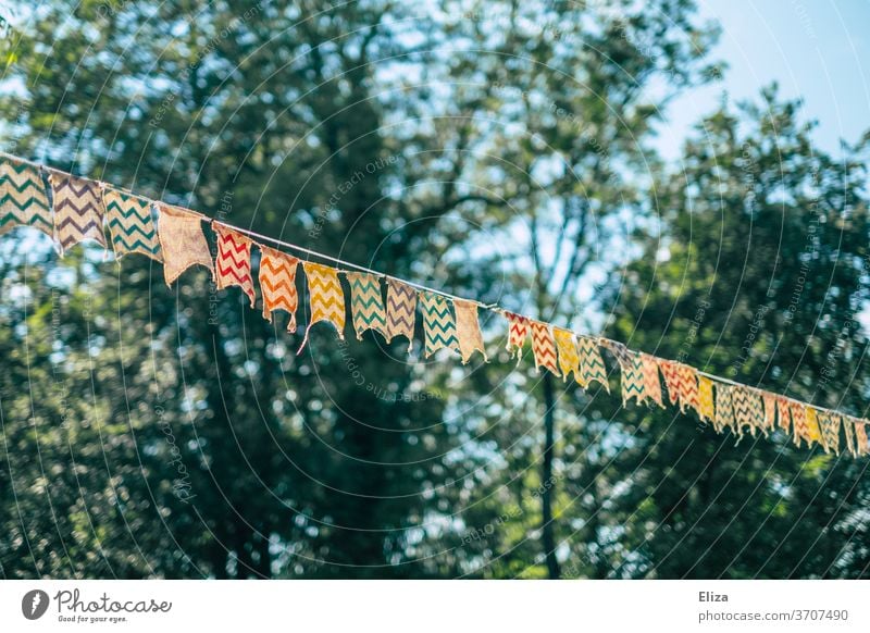 Eine bunte Wimpelkette zwischen Bäumen bei einer Gartenparty Party bung geschmückt Dekoration Geburtstag Kindergeburtstag Girlande Dekoration & Verzierung