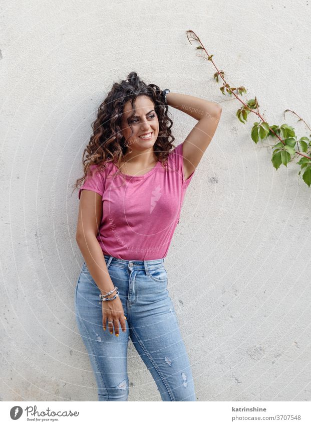 Junge Frauen in T-Shirt und Jeans bleiben in der Nähe einer Mauer jung Mädchen anhaben Attrappe Jeanshose Aufenthalt Wand seine Lächeln Rundhals