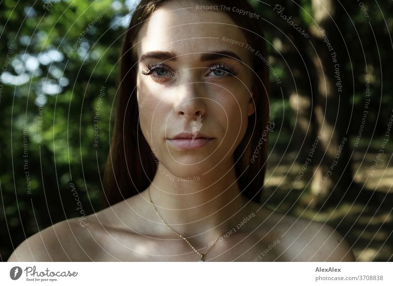 Nahes Portrait einer jungen Frau im Wald Licht sportlich feminin Gefühle emotional Blick in die Kamera Porträt Zentralperspektive Schwache Tiefenschärfe