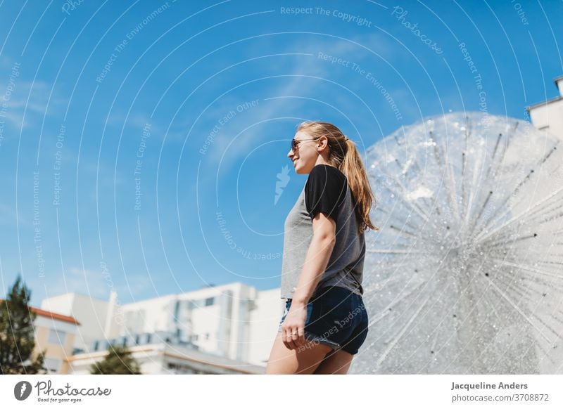 junge Frau schaut in die Ferne am Springbrunnen in der Stadt Junge Frau frau in die ferne sehen springbrunnen stadt Stadtzentrum Häuser Farbfoto Außenaufnahme