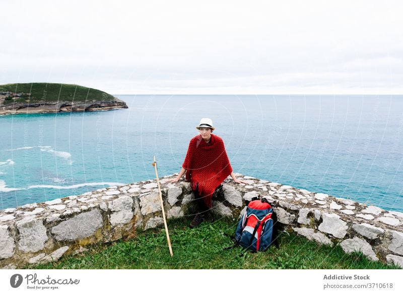 Stilvolle reisende Frau mit Rucksack ruht in der Nähe von Meer Wanderer Backpacker Reisender Pilgerfahrt MEER ruhen Trekking Stein Seeküste camino de santiago