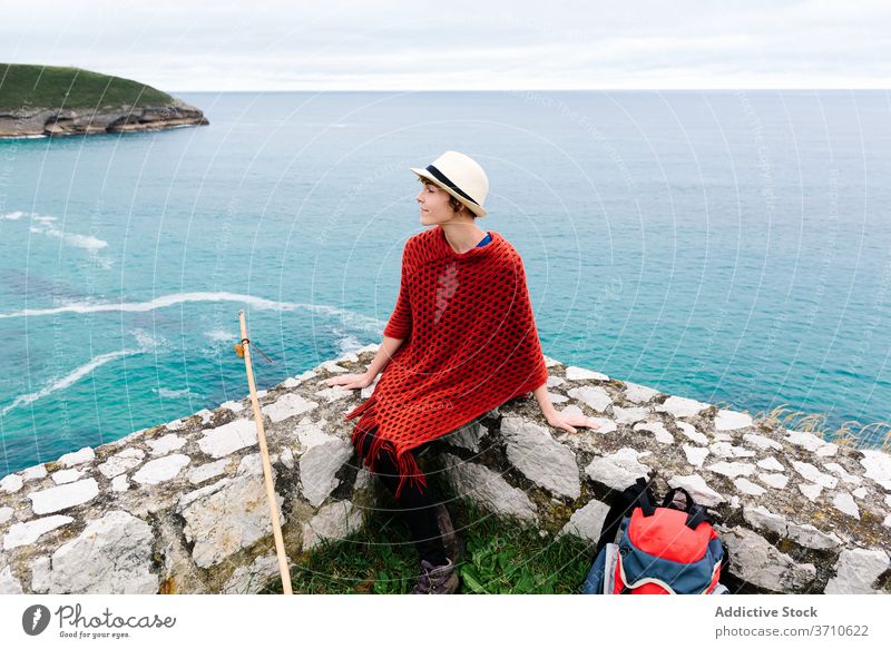 Stilvolle reisende Frau mit Rucksack ruht in der Nähe von Meer Wanderer Backpacker Reisender Pilgerfahrt MEER ruhen Trekking Stein Seeküste camino de santiago