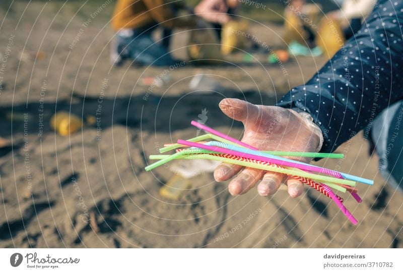 Frau zeigt eine Handvoll Strohhalme, die am Strand gesammelt wurden Detailaufnahme zeigend mikroplastisch Freiwilligenarbeit Reinigen Meeresverschmutzung