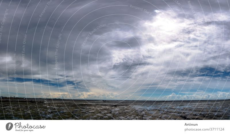 Landschaft mit Schlammstrand, Meer und Himmel. Panorama-Ansicht des Strandes bei Flut und Skyline. Wunderschöne Wolkenlandschaft. Blauer Himmel und weiße Wolken an einem sonnigen Tag. Tropisches Meer. Konzept für Sommerreisen. Der Klimawandel.