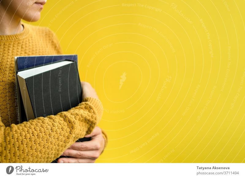 Studentin mit Büchern auf Gelb Frau Schüler Bildung Buch Universität Hochschule gelb lesen Pullover gestrickt Person Erwachsener studierend Menschen Porträt