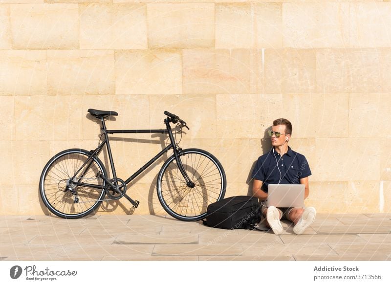 Mann arbeitet auf der Straße in der Nähe seines Fahrrads blond Business Kaukasier Mitteilung Computer Textfreiraum Fahrradfahren Radfahrer Unternehmer