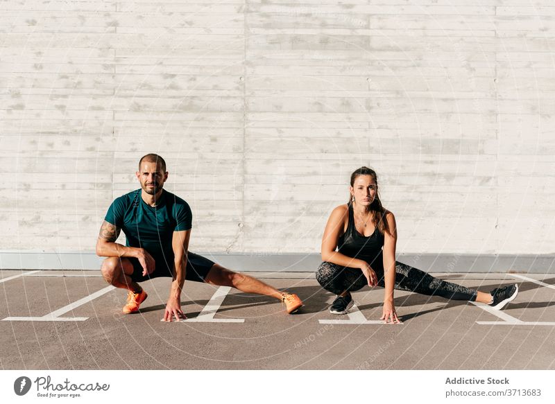 Fit-Sportler trainieren auf der Straße Seitenlonge Training Paar Partnerschaft Gesundheit Athlet Fitness Übung Zusammensein Sportbekleidung Wellness sonnig