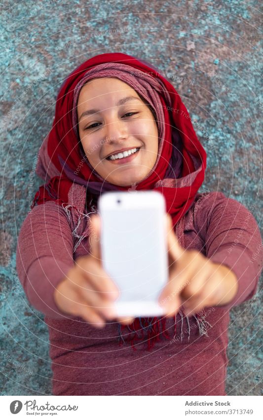 Glückliche Frau nimmt Selfie mit Handy auf der Straße Großstadt benutzend Smartphone Hijab Lächeln heiter arabisch ethnisch Gebäude Browsen Funktelefon online