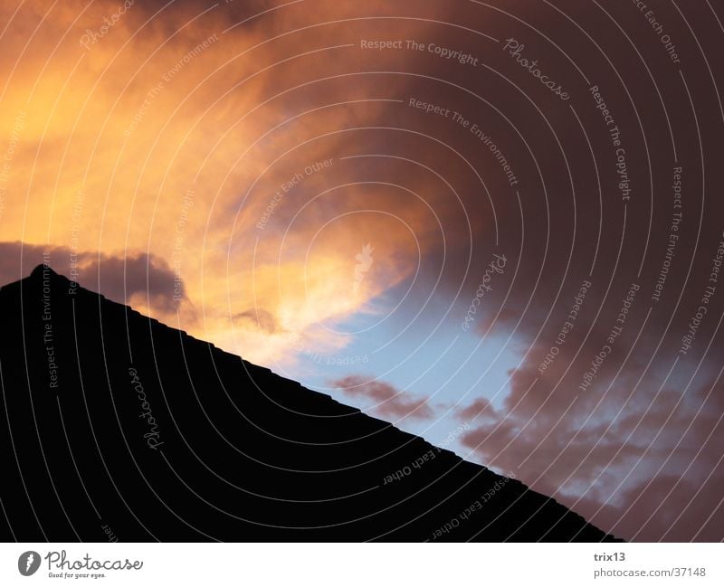 hausdach im Sonnenuntergang Dach Wolken schwarz gelb violett Abenddämmerung Himmel orange blau Strukturen & Formen Wetter