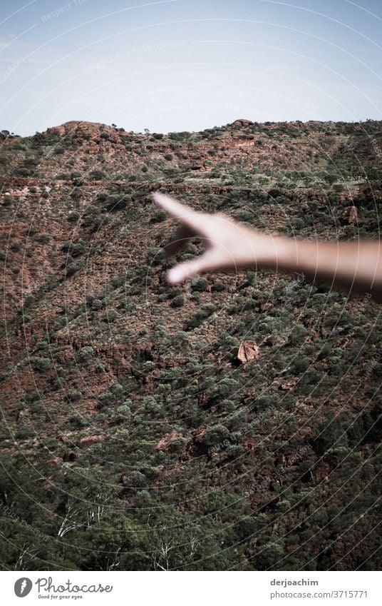 Da drüben zeigt die ausgestreckte Hand im Halbrund des Tales  auf etwas. Im Hintergrund ein felssiger Hang hand aufhalten Farbfoto Zusammensein Mensch