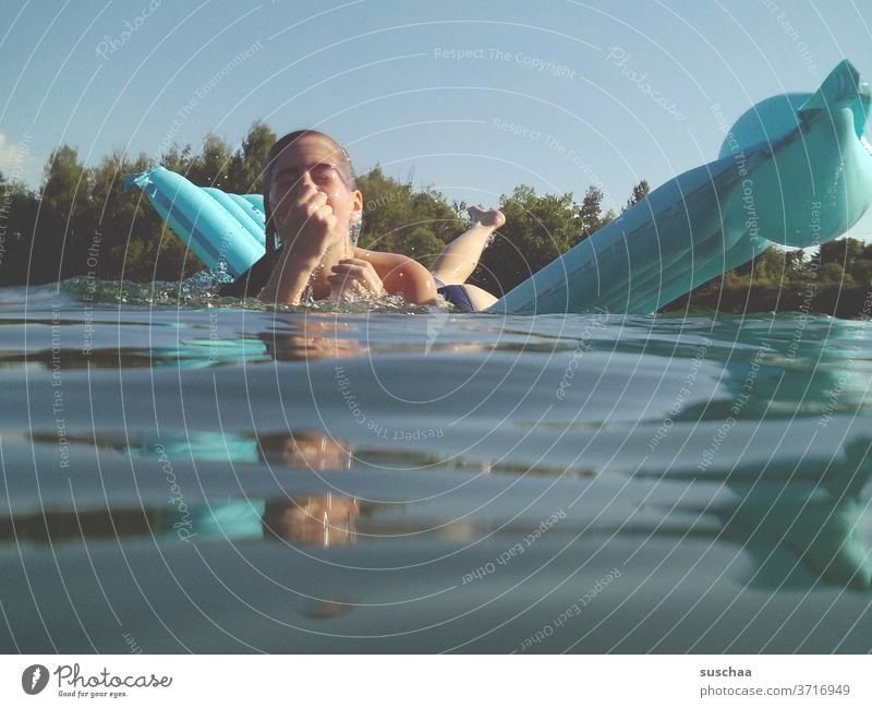 mädchen auf einer blauen luftmatratze an einem heißen sommertag am see kurz vor dem abtauchen Mädchen Kind See Badesee Wasser Luftmatratze schwimmen