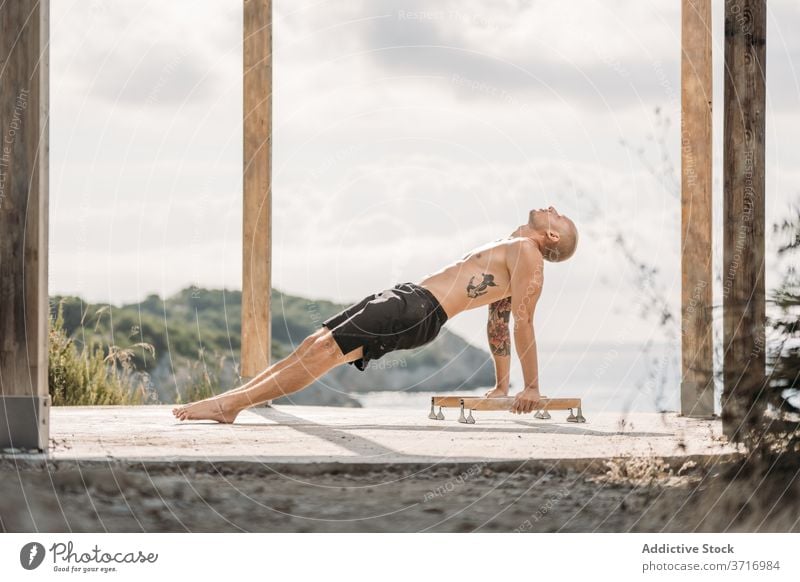 Starker Mann macht Handstand auf Parallelbarren parallel Bar Sportler Gleichgewicht stark muskulös nackter Torso Athlet Kraft männlich Training Sommer Übung