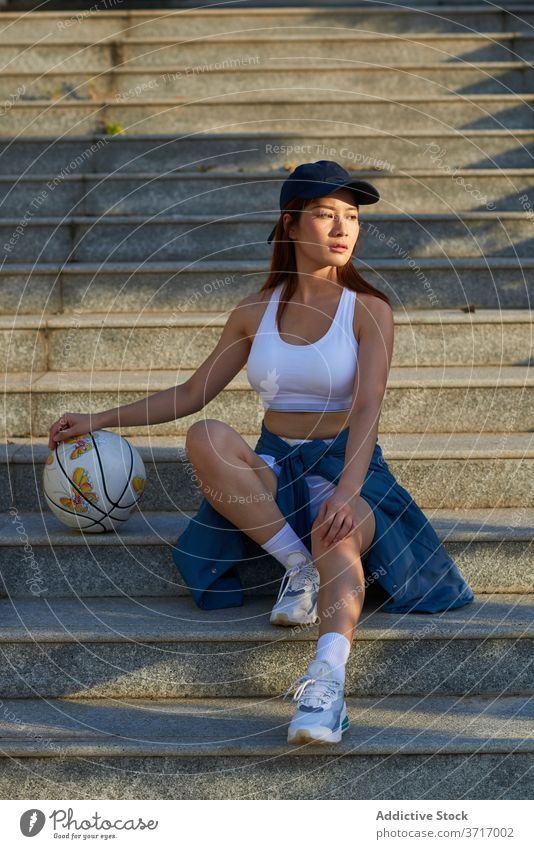 Schlanke Sportlerin mit Basketball auf der Treppe Frau Straße Großstadt Streetstyle Stein Sportbekleidung Athlet asiatisch ethnisch Windstille Schritt