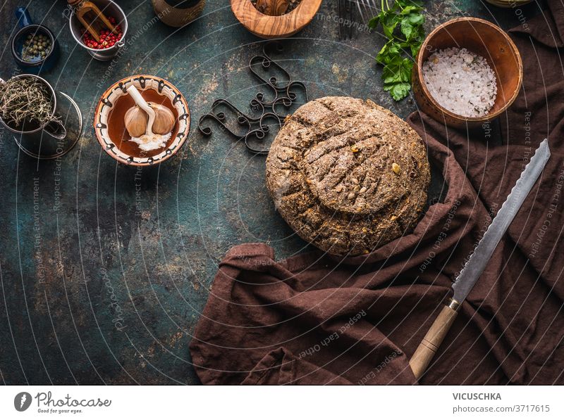 Hausgebackenes Vollkornbrot auf dunklem Küchentischhintergrund mit Messer und Kochwerkzeug selbstgemacht ganz Korn Brot dunkel Hintergrund Essen zubereiten